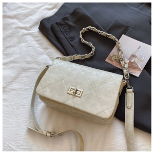 Close-up of cream quilted square bag with gold chain and vintage leather texture
