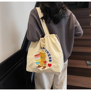 Detail view of cream canvas tote featuring bear embroidery and blue happiness text