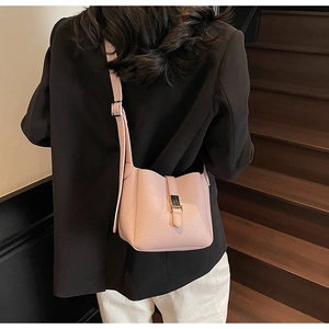 Détail du sac seau rose en cuir grainé avec boucle argentée porté par un mannequin