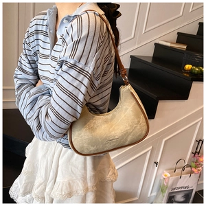 Close-up of a beige crescent underarm bag with vintage texture and brown edge details