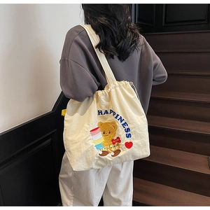 Detailed shot of cream canvas tote bag with embroidered bear and blue Happiness text
