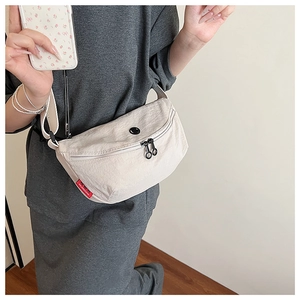 Detail of off-white nylon half-moon crossbody bag with double zippers and red woven label