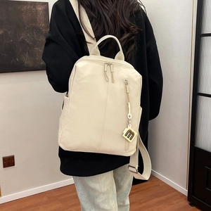 Detail of cream backpack with soft textured leather and stylish letter M pendant charm
