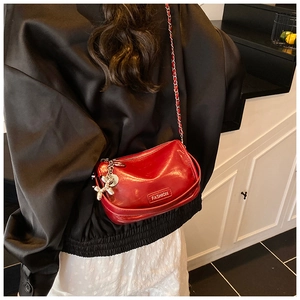 Red glossy patent leather crossbody bag with silver chain strap shown on model back