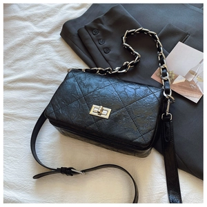Detail of black quilted crossbody bag with silver twist lock and chic leather chain strap