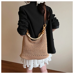 Close-up of woven straw tote bag featuring wooden bead handles for summer beach vacations