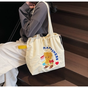 Close-up of beige drawstring tote bag with cute teddy bear and happiness embroidery