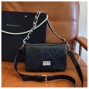 Detail of black quilted leather crossbody bag with pearl chain and silver turn-lock