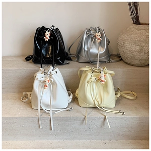 Detail of minimalist bucket backpacks in black, silver, white and yellow with rabbit charms
