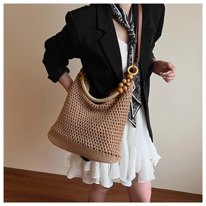Detail view of woven shoulder bag featuring wooden beads and a yellow ring buckle strap