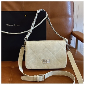 Detail of cream quilted handbag with pearl chain and silver twist lock on leather seat