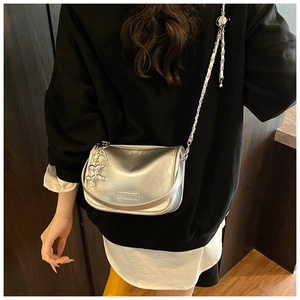 Detail of silver metallic crossbody bag with chain strap and cute dog charm accent