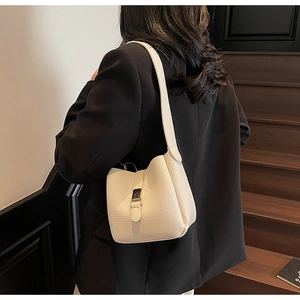 Détail du sac seau blanc crème avec texture en cuir grainé et boucle dorée élégante