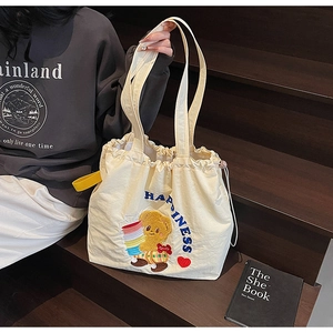 Close-up of beige canvas tote bag featuring teddy bear embroidery and drawstring closure