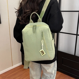 Detail of light green textured backpack with vertical zipper and B-letter charm detail