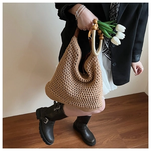 Detail of hand-woven straw bucket bag featuring wooden beads and leather handle accents