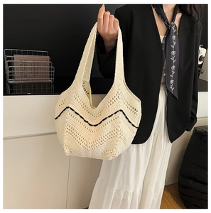 Détail du sac fourre-tout en tricot crème montrant la texture ajourée et les vagues noires