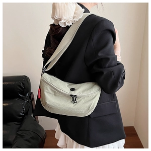 Detail of light green nylon half-moon crossbody bag with adjustable strap on model