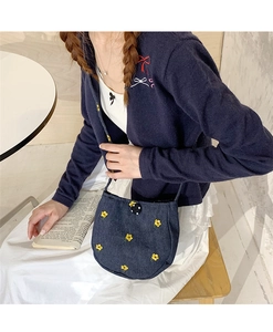 Détail du sac bandoulière en denim bleu avec broderie florale jaune et fine bandoulière