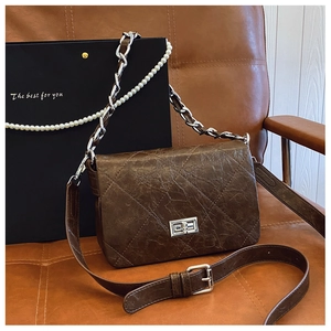 Detail of dark brown quilted leather crossbody bag with silver lock and pearl chain strap