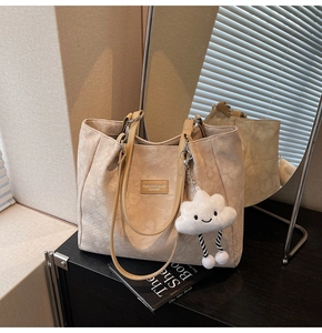 Détail du sac cabas crème avec motif jacquard gaufré et accessoire de charme nuage en peluche