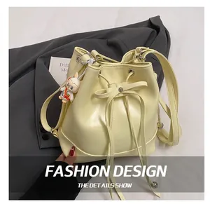 Detail of cream yellow bucket bag featuring drawstring closure and cute bunny charm