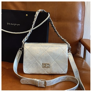 Detail of silver quilted handbag featuring classic diamond pattern and metallic chain strap