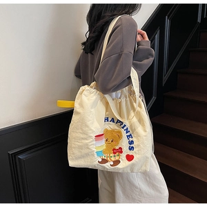 Close-up of cream canvas tote bag with brown bear embroidery and happiness text
