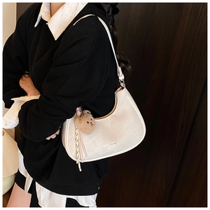 Detail of white half-moon hobo bag with teddy bear charm and logo print on soft material