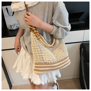 Detail of hollow woven shoulder bag with round wooden beads on a white hobo bag