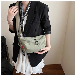Detail of sage green nylon crescent bag showing wide strap and black dual zippers