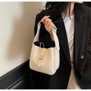 Detail showing litchi grain texture on beige soft leather bucket bag with silver buckle