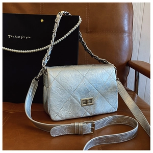 Detail of silver quilted leather bag with metallic finish and metal turn-lock closure