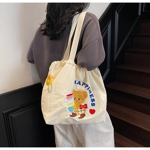 Detail of beige tote bag with cute bear embroidery and drawstring closure for women
