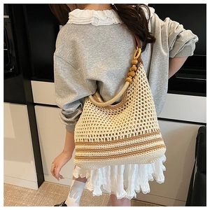 Detail of woven beach tote with wooden beads on shoulder straps and beige stripes