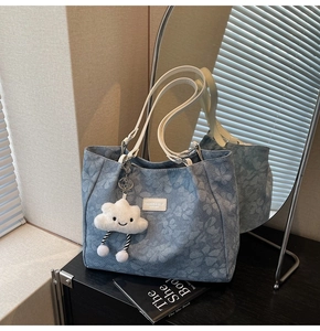 Détail du cabas en denim à fleurs avec anses en cuir blanc et accessoire nuage