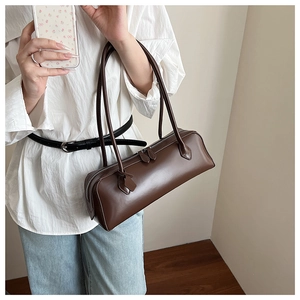 Brown rectangular shoulder bag styled with white shirt and jeans in a minimalist setting