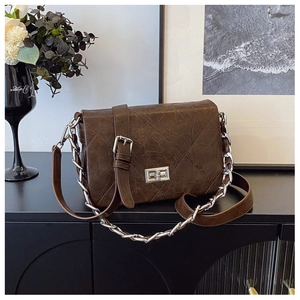 Close-up of quilted dark brown crossbody bag featuring vintage texture and silver metal chain