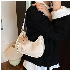 Detail of cream crescent underarm bag with cute bear plush and striped silk scarf