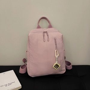 Detail of pink nylon backpack featuring water-resistant fabric and a yellow logo charm