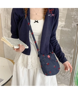 Détail du sac à bandoulière en jean bleu foncé avec broderies cerises rouges et boucle