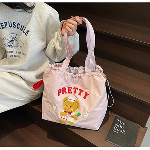 Detail of pink nylon tote bag featuring cute cartoon bear embroidery and drawstring