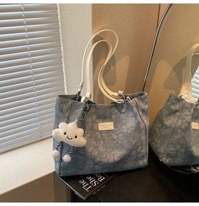 Détail du sac cabas à fleurs bleues avec anses blanches et charme nuage peluche