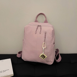 Macro detail of pink textured nylon backpack featuring double zippers and functional pockets