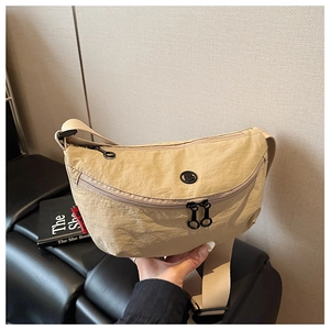 Close-up of beige nylon crossbody bag with black dual zippers and red side label detail
