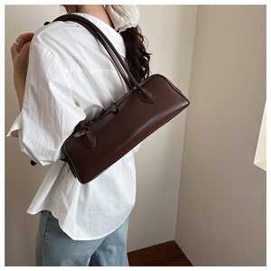 Detail view of smooth brown faux leather texture on a stylish baguette underarm bag
