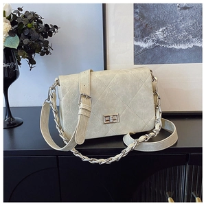 Close-up of beige quilted crossbody bag with silver twist lock and chain strap detail