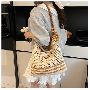Detail of beige hollow woven hobo bag with dark stripes and wooden bead handle accents