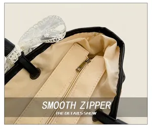 Détail du sac fourre-tout en paille noire montrant la doublure en tissu beige et le zip fluide