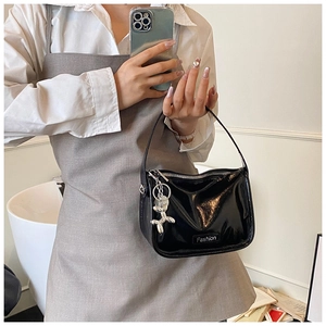 Detail of black patent leather crossbody bag with silver balloon dog charm and fashion tag